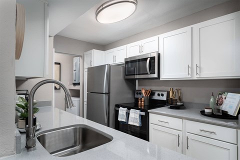 A modern kitchen with a stainless steel sink and white cabinets.