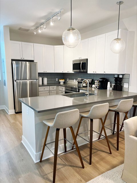 A kitchen with white cabinets and a stainless steel refrigerator.