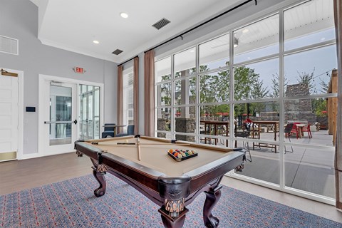 A pool table in a room with a view of the backyard.