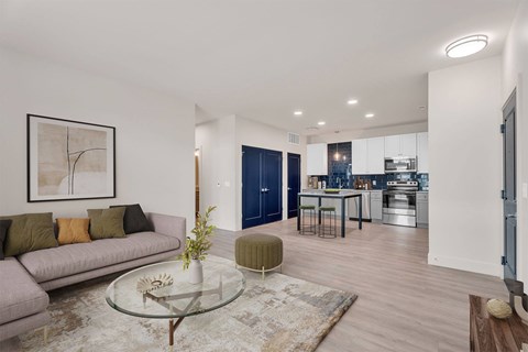 A modern living room with a glass coffee table and a grey sofa.