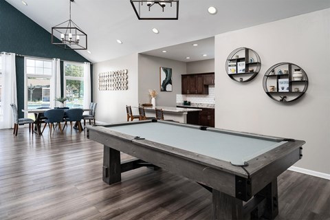a pool table in a living room with a kitchen and dining area