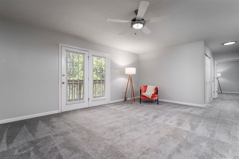 an empty living room with a ceiling fan and a chair