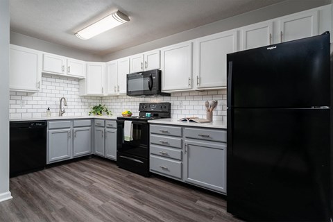 a kitchen with white cabinets and a black refrigerator
