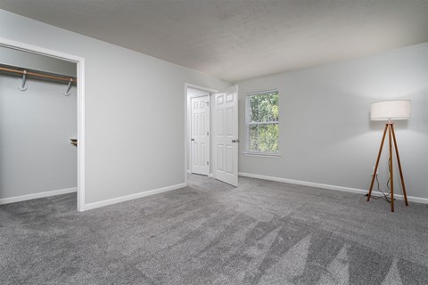 an empty room with a lamp and a door to a closet