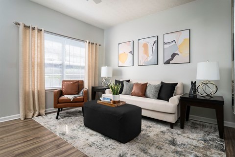 A living room with a brown chair, a white couch, and a black ottoman.