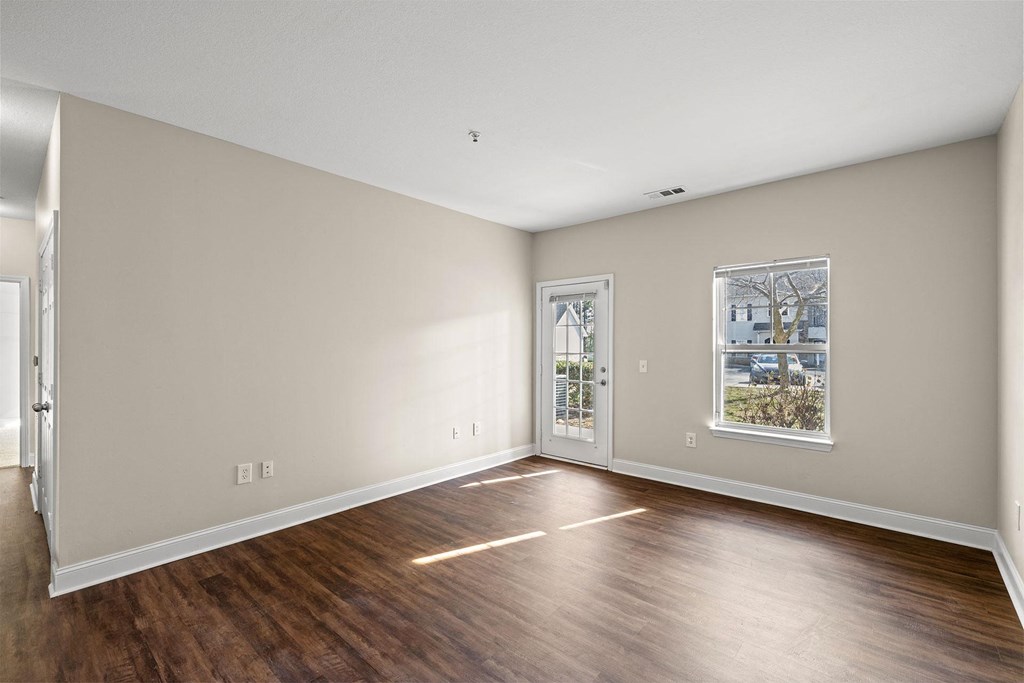 A room with a wooden floor and a window with a picture of a house on it.