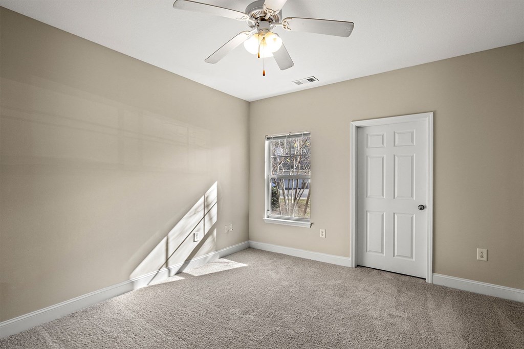 A room with a fan, carpet, and a door.