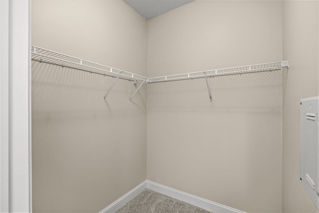 A white closet with a white shelf and a white door.