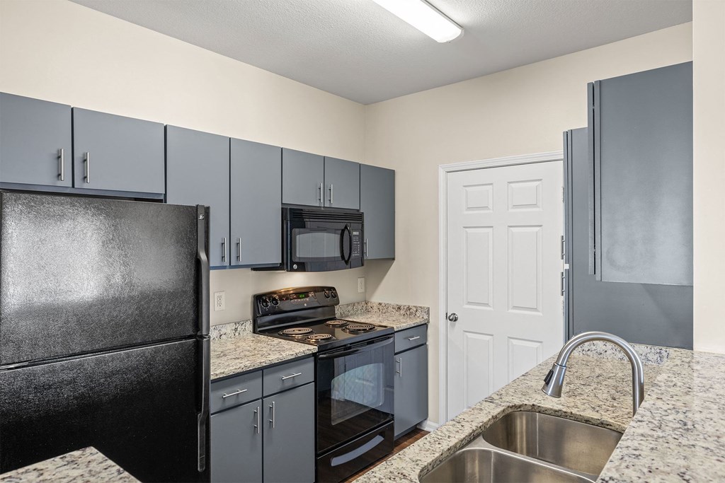 A kitchen with a black refrigerator and a white door.