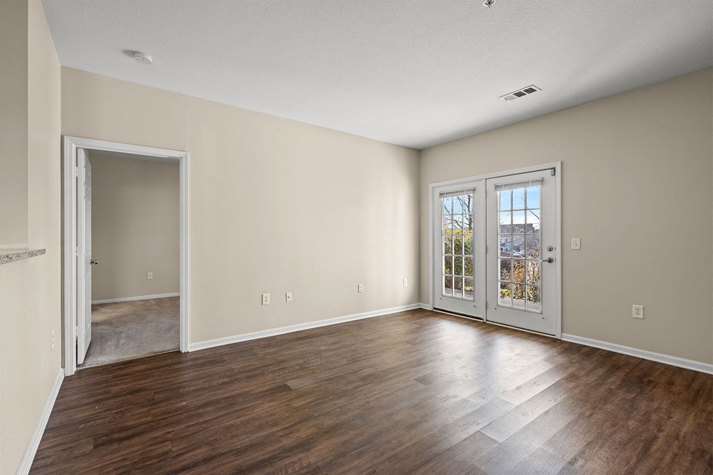 A room with a wooden floor and a door leading to another room.