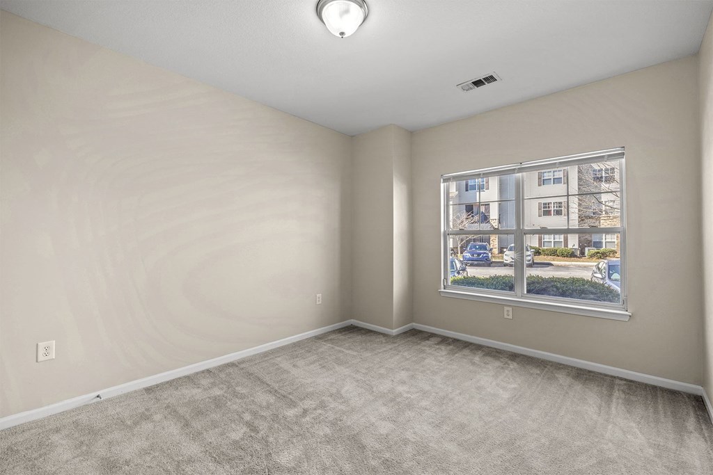 A room with a window showing a view of a street with cars and houses.