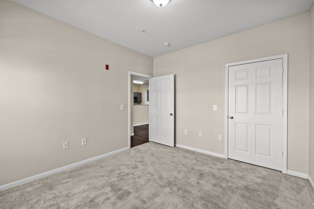 A room with a carpeted floor and two white doors.