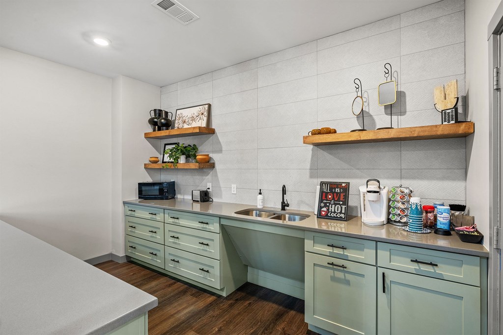A kitchen with green cabinets and a white countertop.