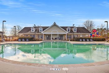A large swimming pool in front of a building with a playground in the background.