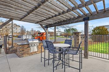 A patio with a table and chairs under a wooden pergola.