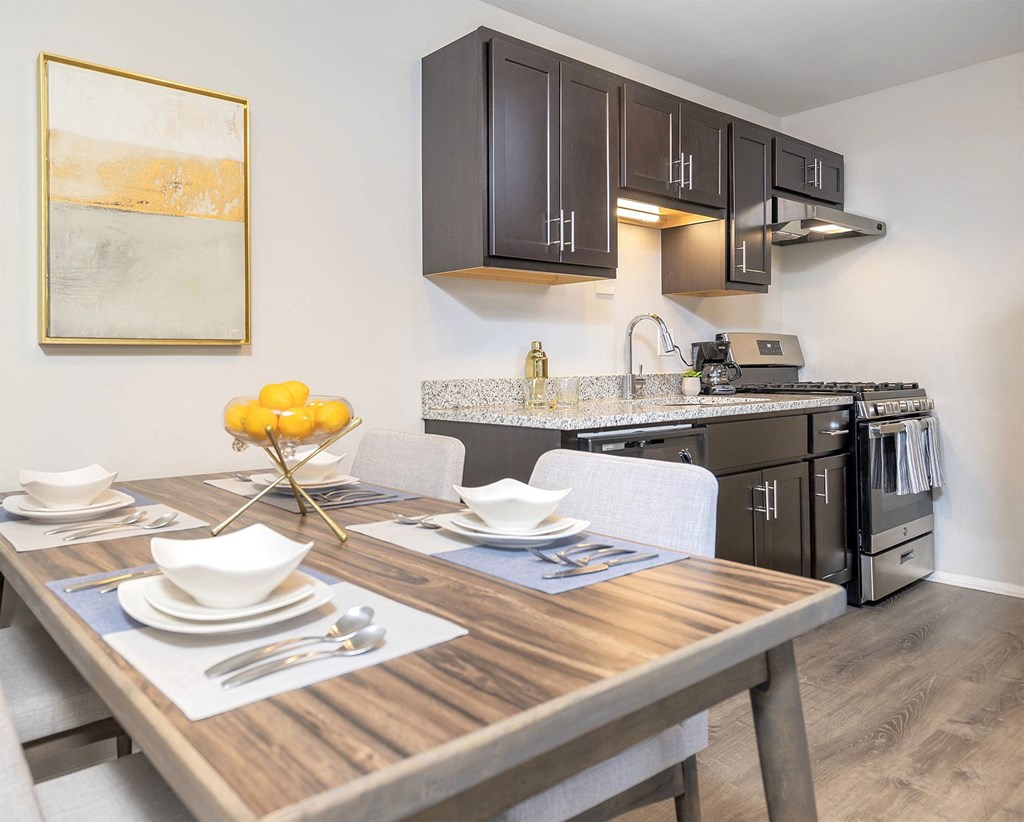 apartment kitchen with dark brown wood cabinets and attached dining area and table