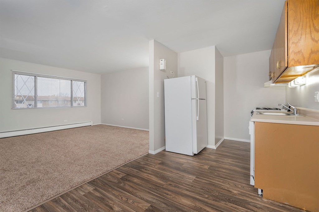 kitchen with wood cabinets and white fridge and attached living room