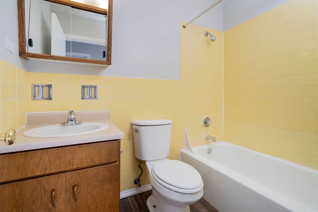 full bathroom with brown cabinet and yellow tile walls
