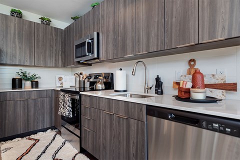 A modern kitchen with dark wood cabinets and stainless steel appliances.