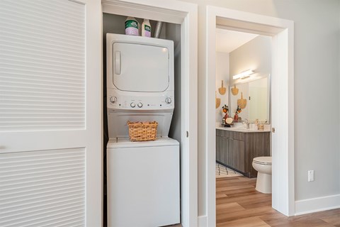 A white washing machine is in a small space between two walls.