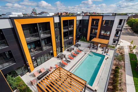 A modern apartment complex with a pool and outdoor seating area.