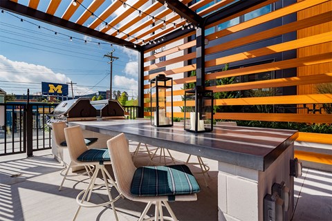 A patio with a table and chairs under a striped awning.