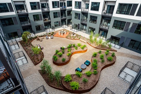 A courtyard with a circular garden and a bench in the middle of a courtyard surrounded by buildings.