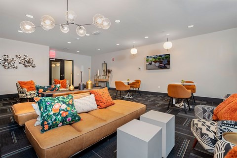 A living room with a brown couch and orange pillows.