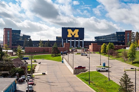 A parking lot in front of a large building with a sign that reads "M".