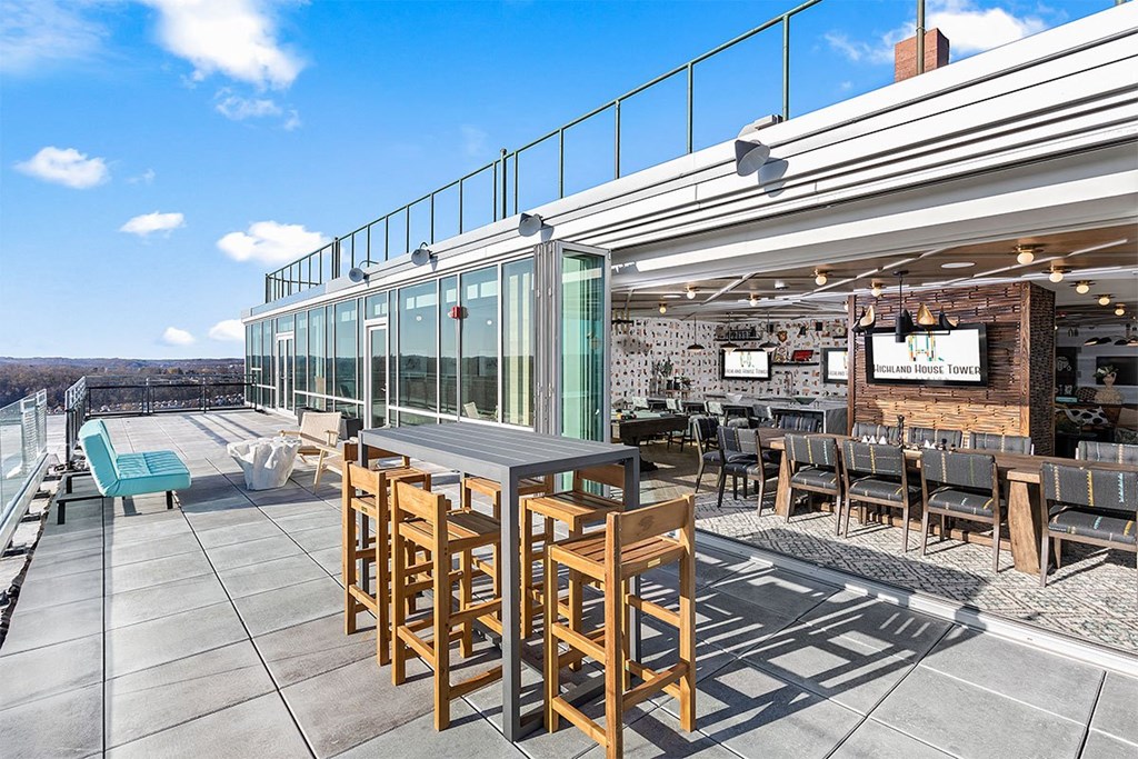 a rooftop patio with tables and chairs and a tv