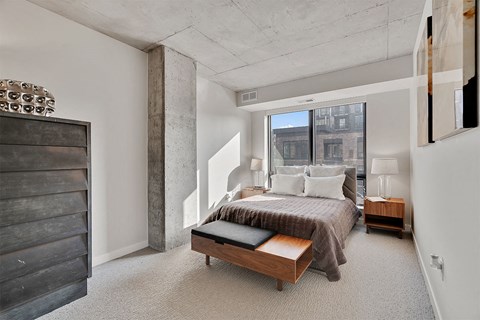 A bedroom with a large bed and a wooden bench.