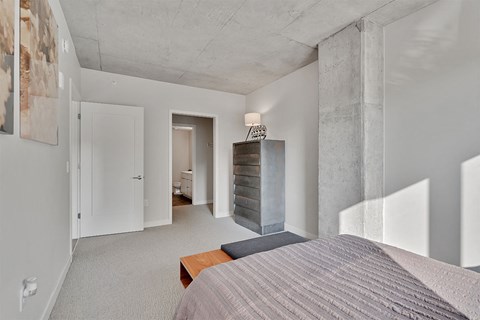 A bedroom with a bed, dresser, and a painting on the wall.