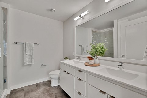 A white bathroom with a toilet, sink, and mirror.