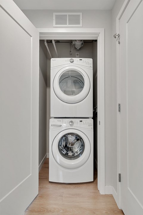 A white washing machine and dryer in a narrow laundry room.