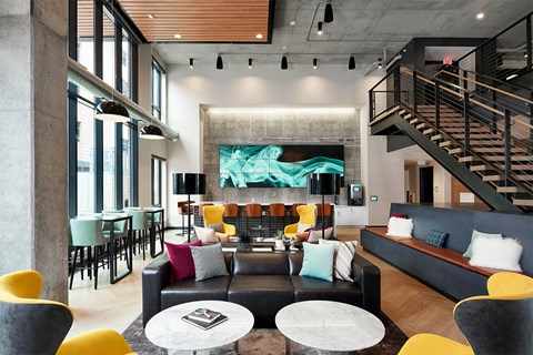 A modern living room with a staircase and a large screen on the wall.