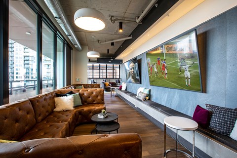 A sports bar with a large screen TV and comfortable seating.