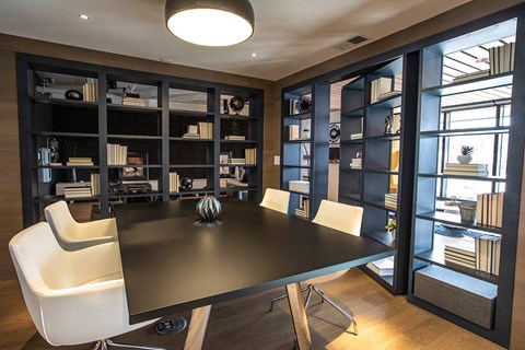 A modern dining room with a black table and white chairs.