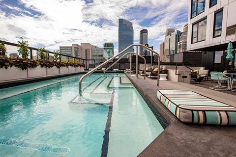 A pool with a slide and a city skyline in the background.