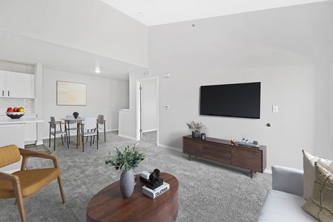 A living room with a brown chair, a grey vase, a book, and a remote control on a wooden coffee table.
