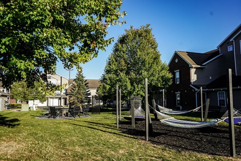 A hammock is strung between two poles in a yard.