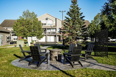 A set of four chairs and a table are arranged around a fire pit.