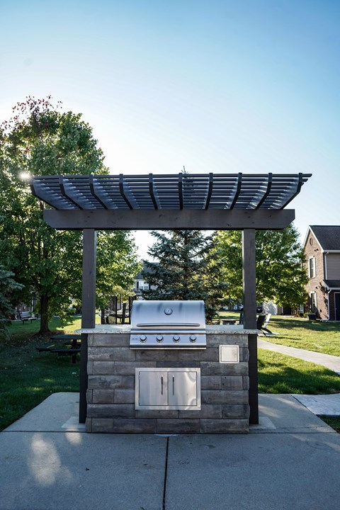 A small outdoor kitchen with a grill and sink.