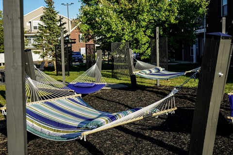 Three hammocks are strung between two wooden posts.