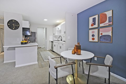 a living room and kitchen with a table and chairs and a clock