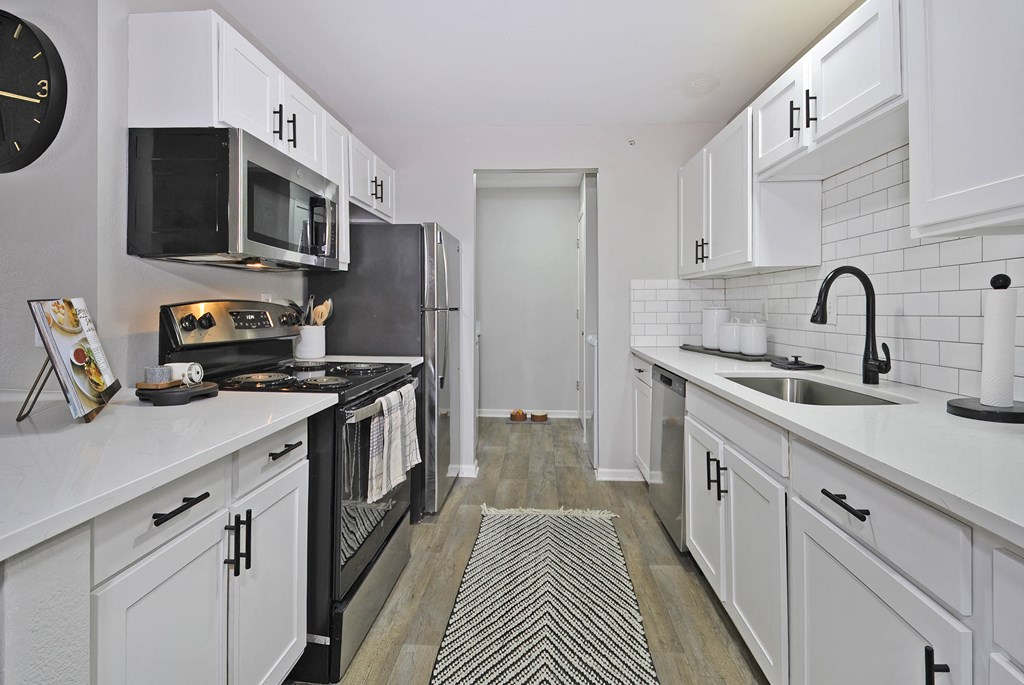 a renovated kitchen with white cabinets and black appliances