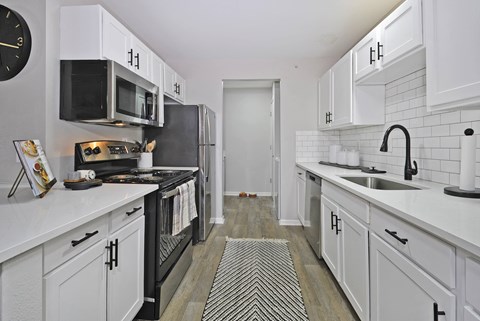a renovated kitchen with white cabinets and black appliances