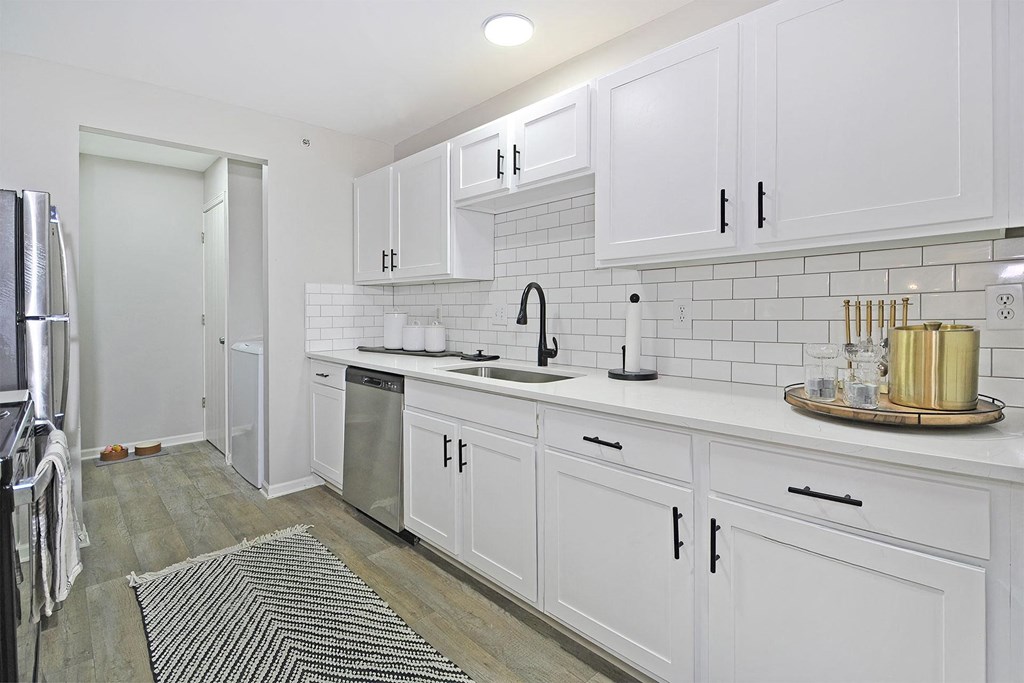 a white kitchen with white cabinets and a stainless steel refrigerator