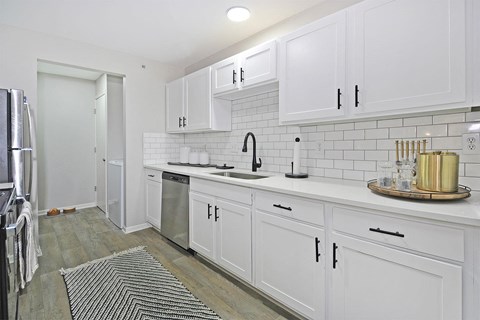 a white kitchen with white cabinets and a stainless steel refrigerator
