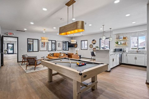 a pool table in a living room with a kitchen