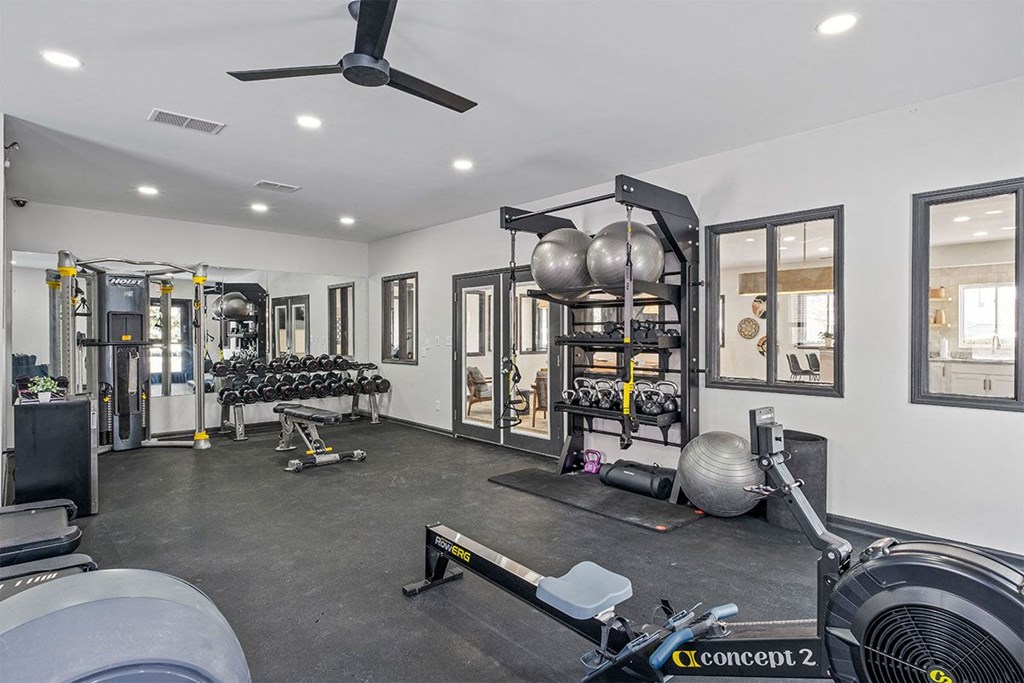 a home gym with weights and machines and a ceiling fan